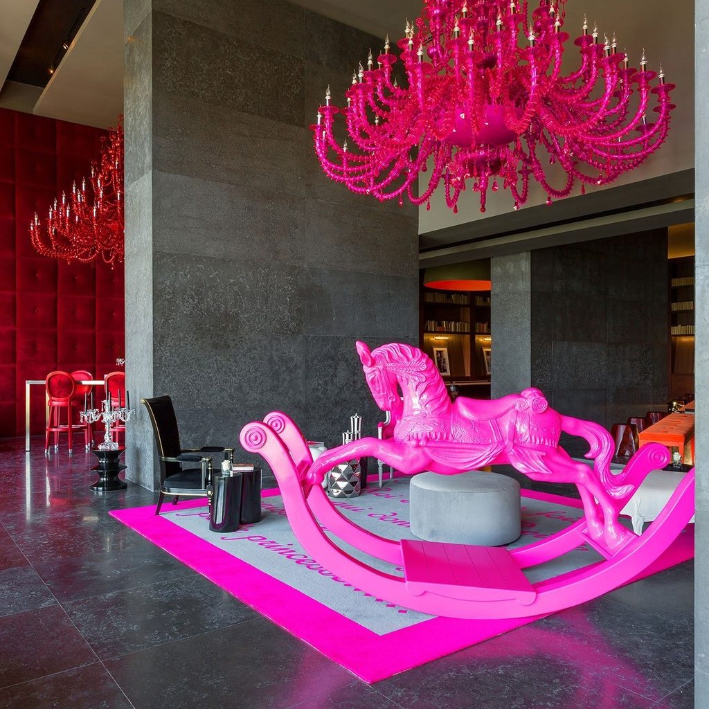 Balancín rosado de adulto y chandelier fucsia en el lobby de Yoo Panama, diseño de autor de Philippe Starck